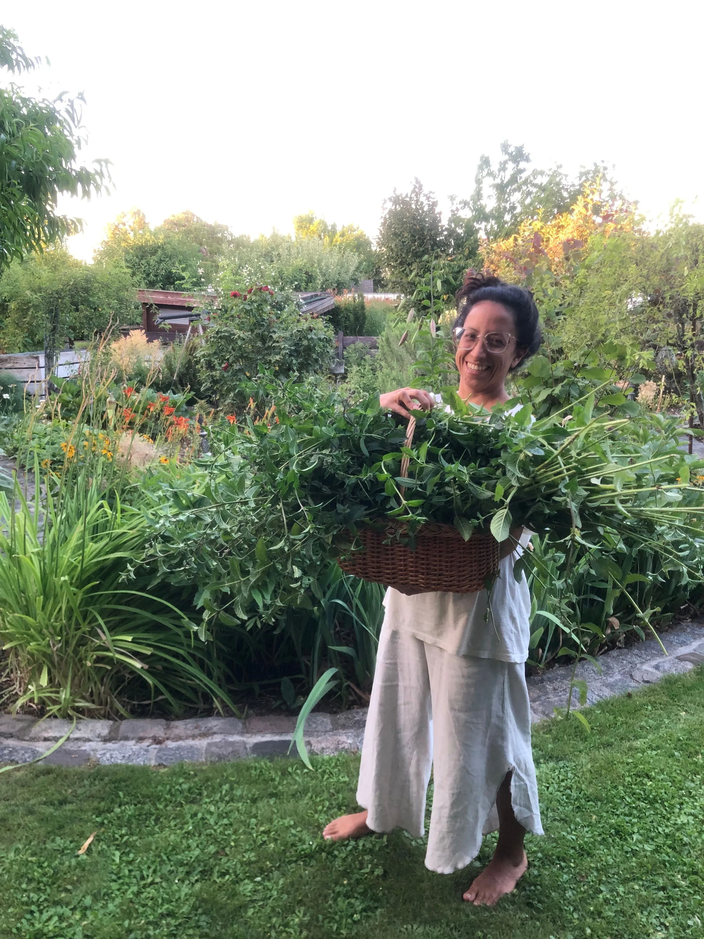 Frau mit einem Korb voller frischer Kräuter im Garten